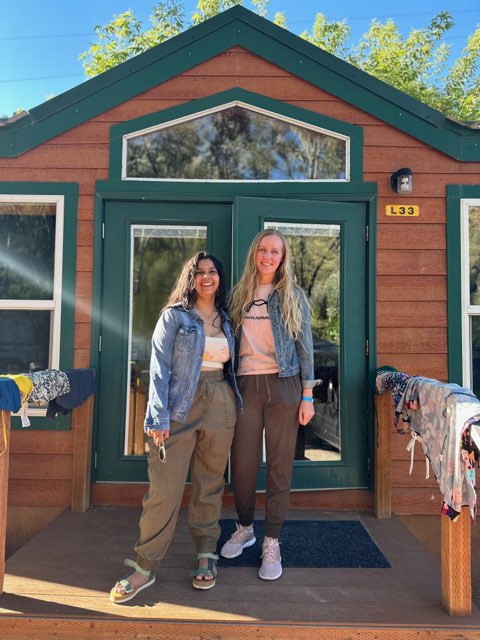 Two residents posed in front of a cabin