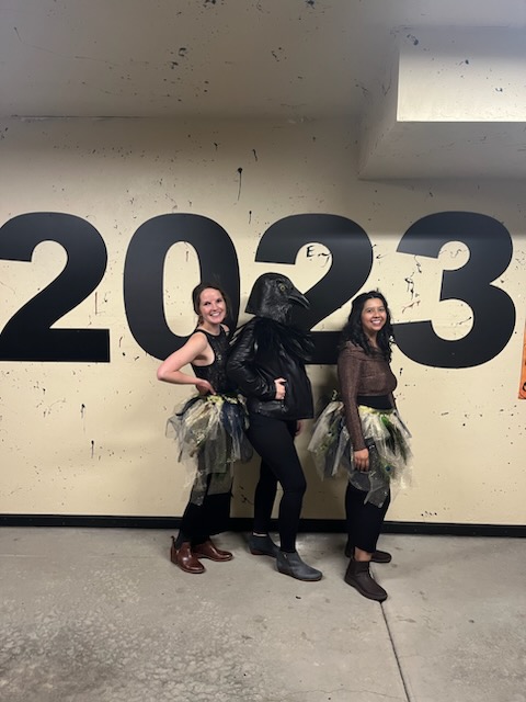 Three residents in costumes posing in front of a wall that reads "2023"